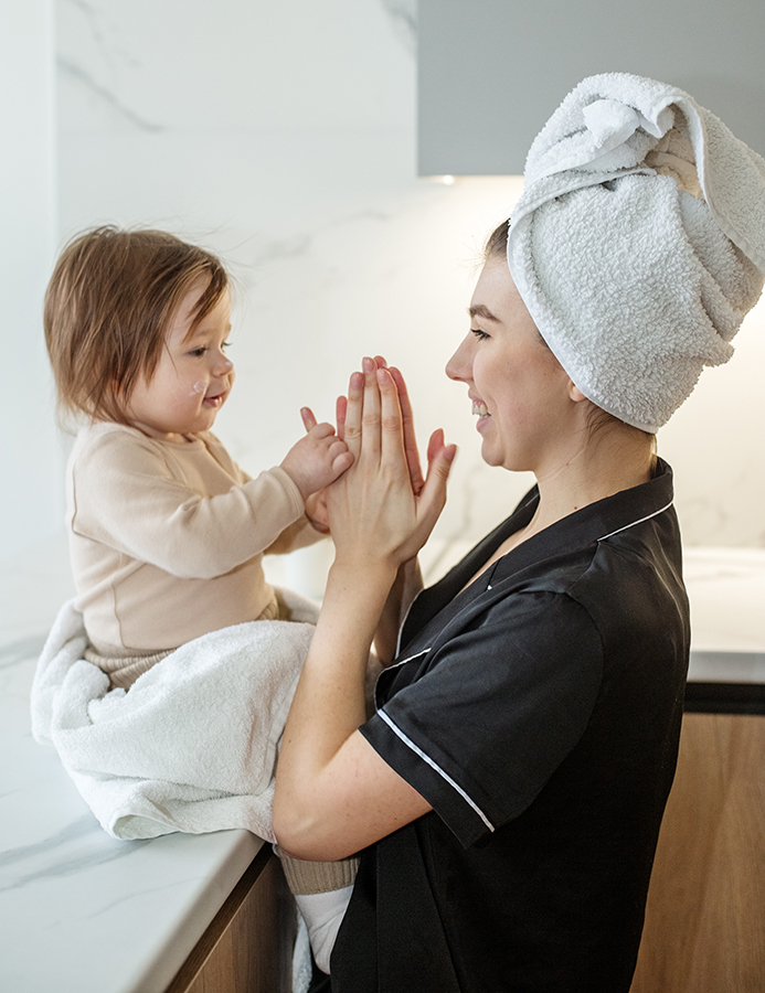 Woman with girl in the sink playing with their hands after shower.